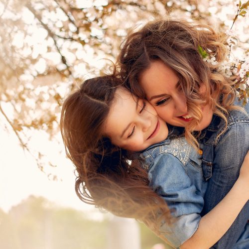Fashionable mother with daughter. Family in a spring park. Woman in a blue shirt