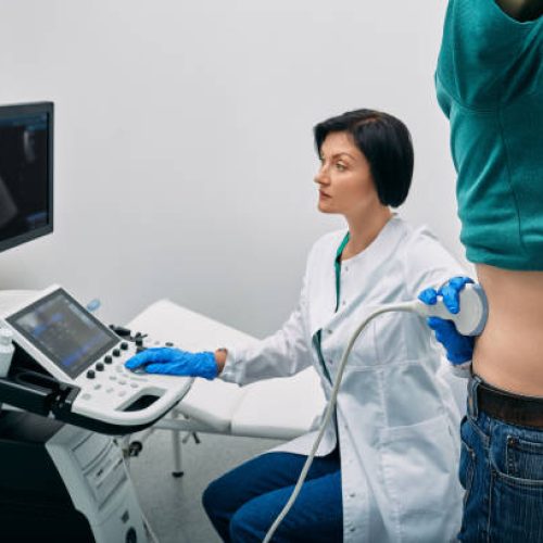 Male patient getting kidneys sonography exam standing near ultrasound specialist and ultrasound machine at hospital. Ultrasound of kidneys